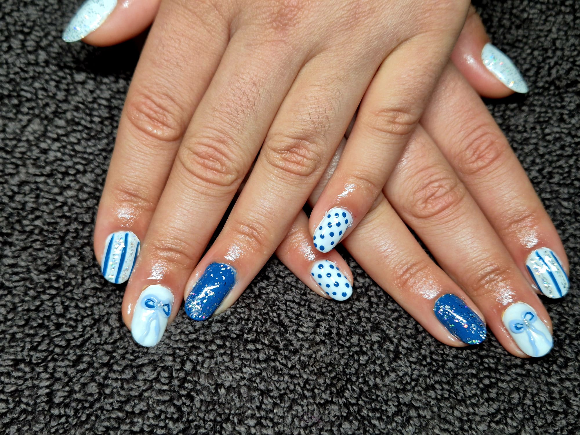 Blue and white nails with dots, bows and glitter stripes