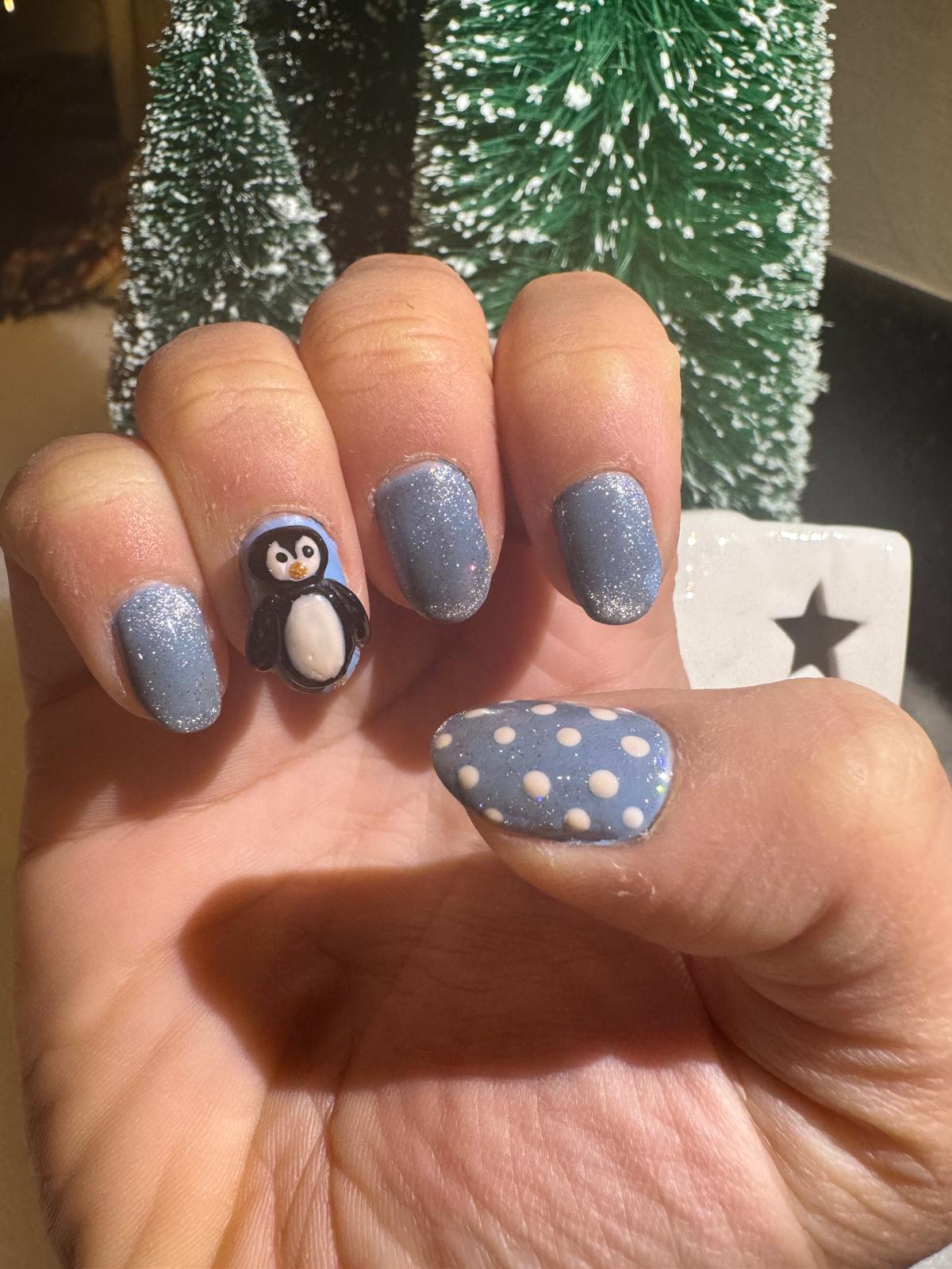 Penguin Christmas nail art with glitter blue and polka thumb